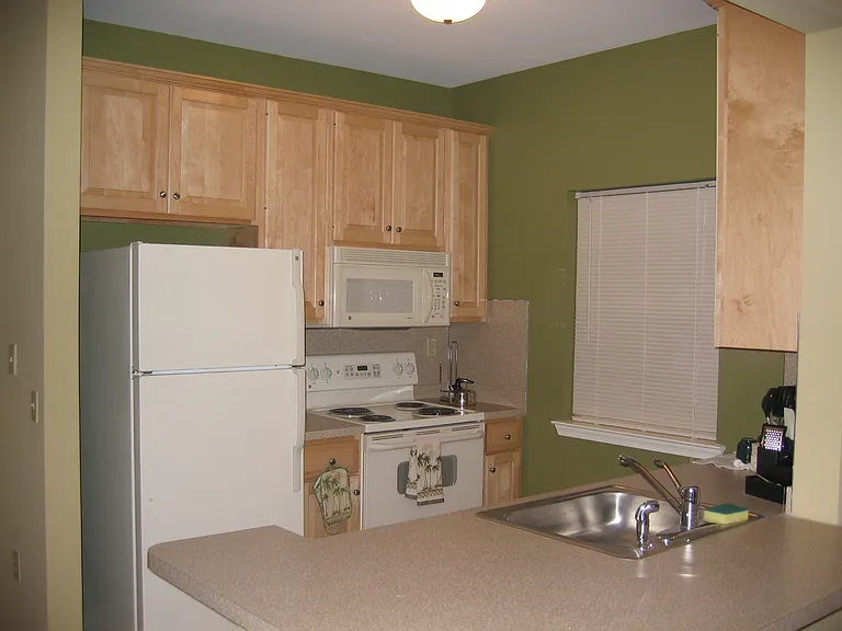 Solid natural maple kitchen and bath cabinetry in Henderson Square II. White appliances are standard.