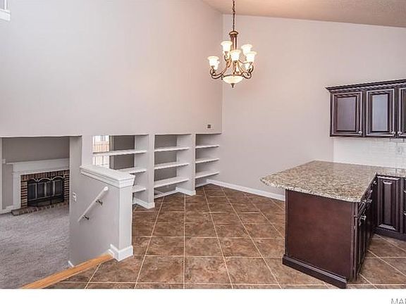 A glimpse of the Dining Area with multi-tiered chandelier.  Tremendous wall display area for art and your collections in the open concept divider. Open concept allows site lines to all of the entertainment areas.  Notice the Fireplace in the Great Room.