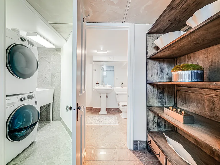 Laundry room with utility sink and lower-level full bath access