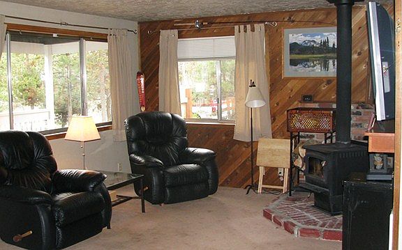 Open living area boasts large windows all around to let the outside views in. Cozy knotty pine, bric