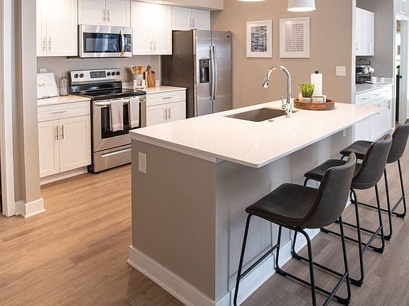 Interior of Champion Reserve Townhome with view of well equipped kitchen with stainless steel appliances, quartz countertops, and breakfast bar/kitchen island.