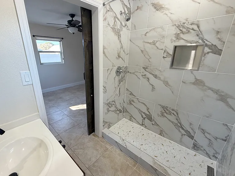 A newly installed standing shower with full tile surround. (Angle 3)