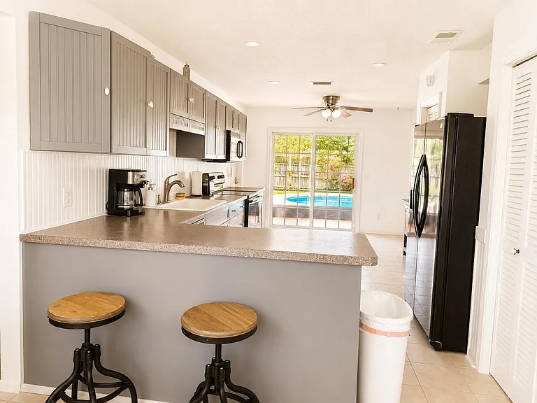 Kitchen with breakfast bar seating, ample cabinet storage, full-size appliances, and patio access through sliding doors.