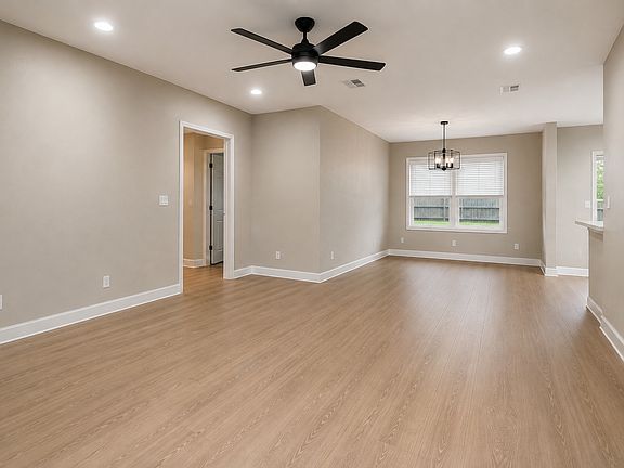 Spacious open living area with new flooring, recessed lighting and matte black ceiling fan.