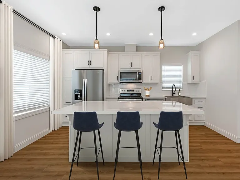Freestanding Home kitchen with white cabinetry, white quartz countertops, white subway tile backsplash, stainless steel appliances, and hard surface flooring