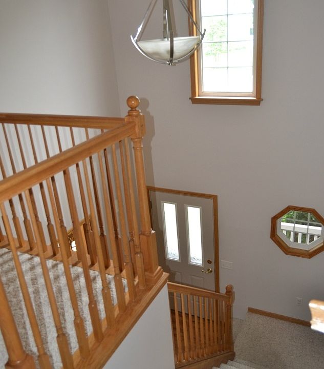 The front entry is two stories.  It features a couple unique windows and a nice chandelier.  The open staircase is trimmed out in Oak to match the wood floors.