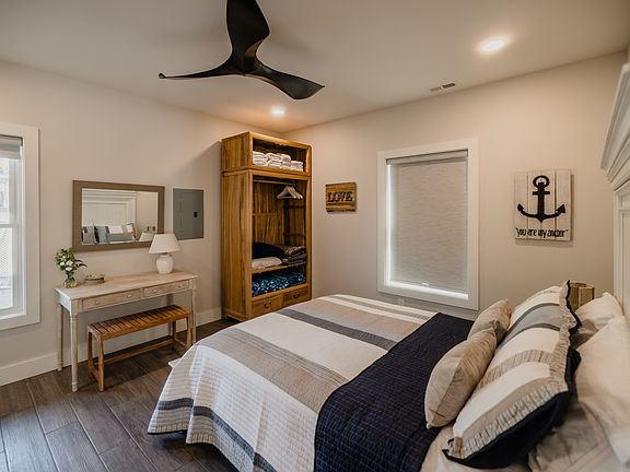 Primary bedroom with a queen-sized bed, ceiling fan, closet, and desk