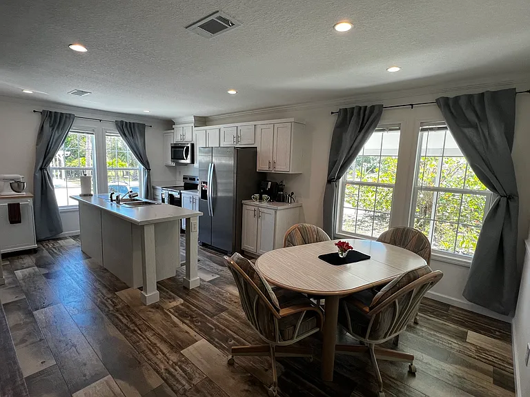Kitchen view and Dining room with dining table and four swivel rolling chairs. Cpmes with two extra swivel rolling chairs.