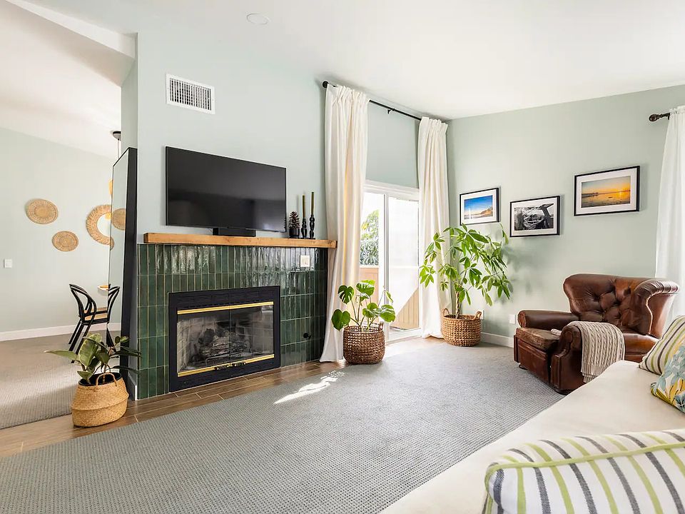 Living Room with gas fireplace, smart TV and Restoration Hardware couch, drapes and captain chair