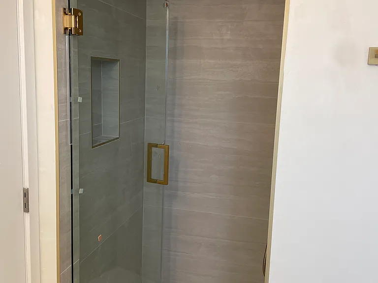Bathroom-2 custom-designed vanities, Delta gold hardware, large-format tile, and modern rainfall showers