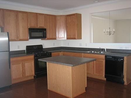 Like new kitchen with black appliances, hardwood floors and island