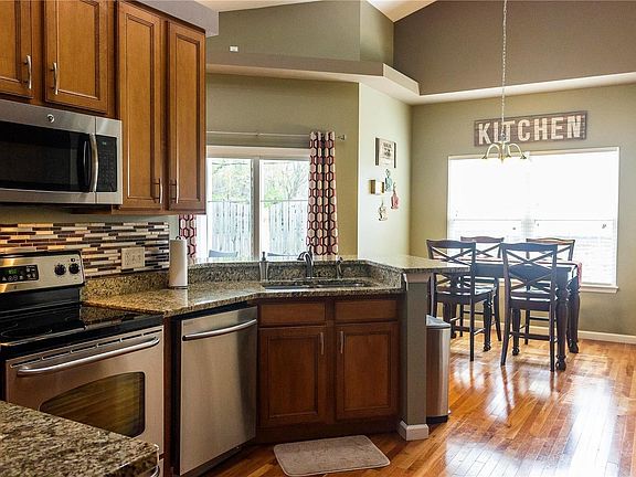 Eat-in kitchen features custom 42" cabinets, granite countertops, backsplash, stainless steel appliances, planning desk, and har