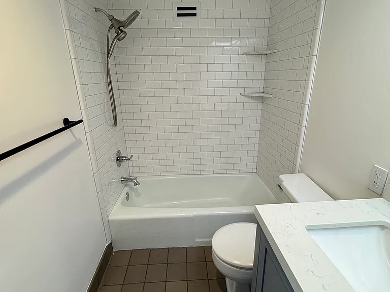 Recently updated bathroom features new tile, updated vanity, and bright lighting.