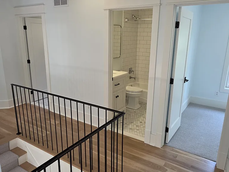 Upper hallway. Rear bedroom to the right. Common bathroom center then laundry room to the left. Primary bedroom is far left. Front bedroom is behind where photo is taken from.