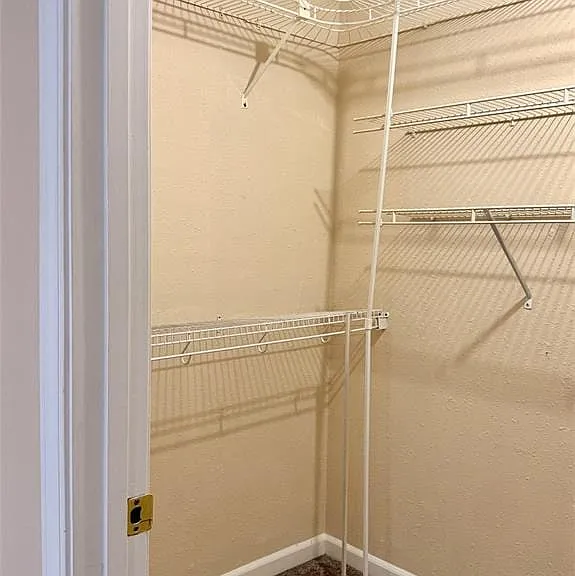 Corner closet featuring white wire shelving and carpeting