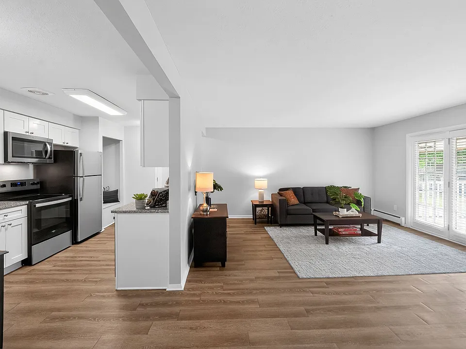 Elegant open-concept living room and kitchen with sleek appliances, modern decor, and abundant natural light.