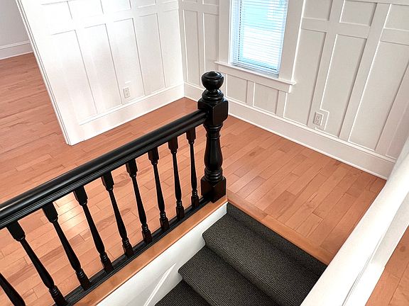 Main hall entry stairs with classic details. Original bannister + newly added wainscoting and crown moulding.