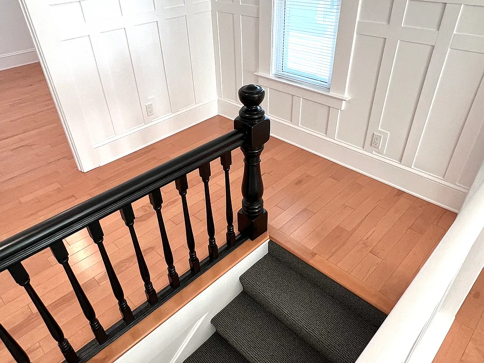 Main hall entry stairs with classic details. Original bannister + newly added wainscoting and crown moulding.