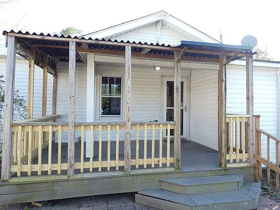 Covered back deck looks over the yard, detached garage, and oversized storage shed.
