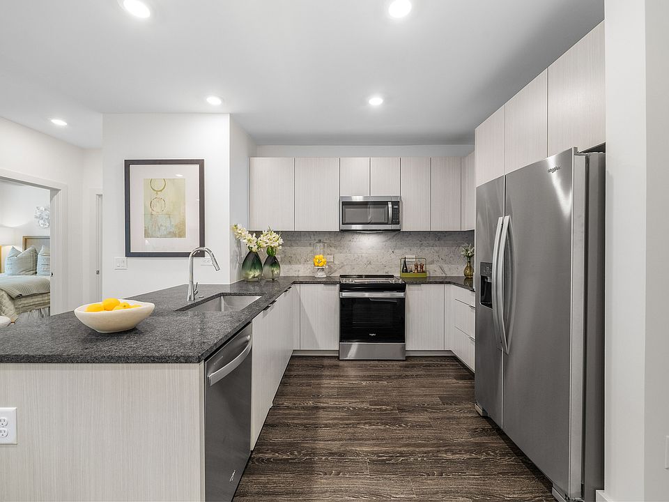 Modern kitchen with sleek appliances, elegant granite countertops, and stylish cabinetry, adjacent to a cozy bedroom.
