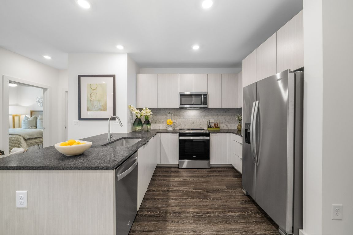 Modern kitchen with sleek appliances, elegant granite countertops, and stylish cabinetry, adjacent to a cozy bedroom.