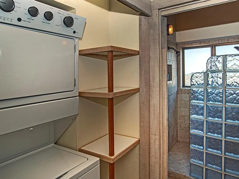 Looking past the Whirlpool washer with gas dryer to the walk in shower room