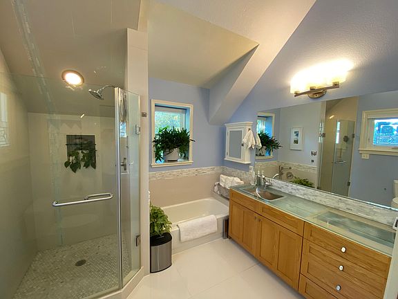 Primary bedroom ensuite bathroom with oversized rainfall shower, full tub, custom glass vanity top and hammered nickel sink.