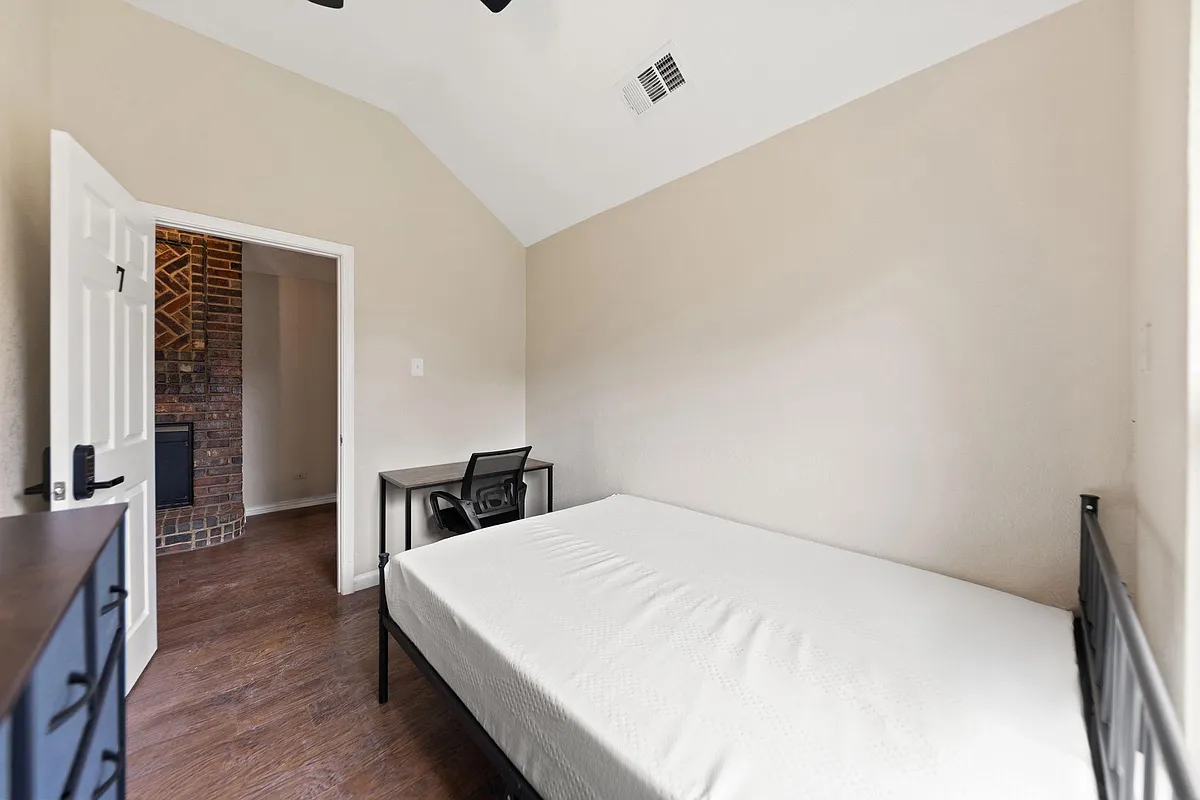 Private bedroom with vaulted ceiling, wood-style flooring, and space for a bed plus a dedicated desk setup. - Debbie Cir