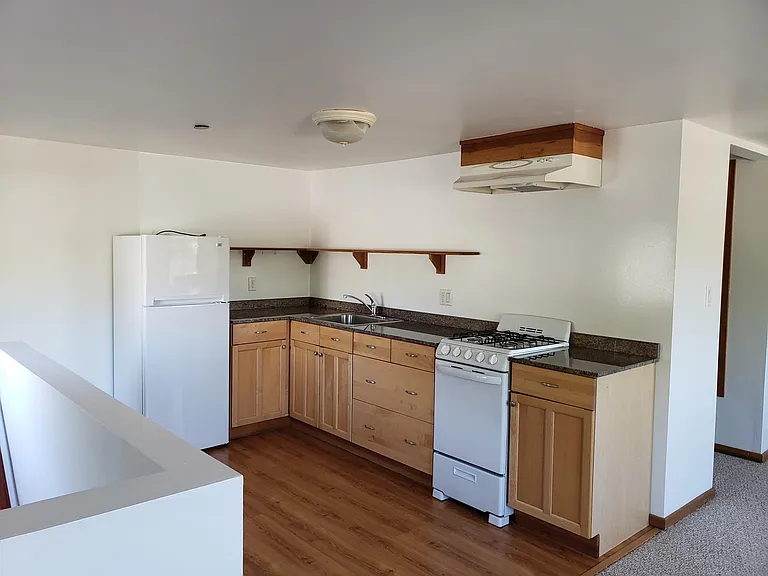 Kitchen with granite countertops. Full size refrigerator. 4 burner gas stove and oven.