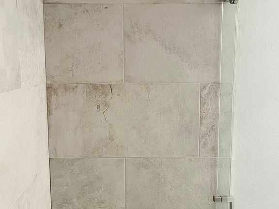 En Suite master bathroom shower with floor-to-ceiling luxury porcelain tile and brushed nickel trim.