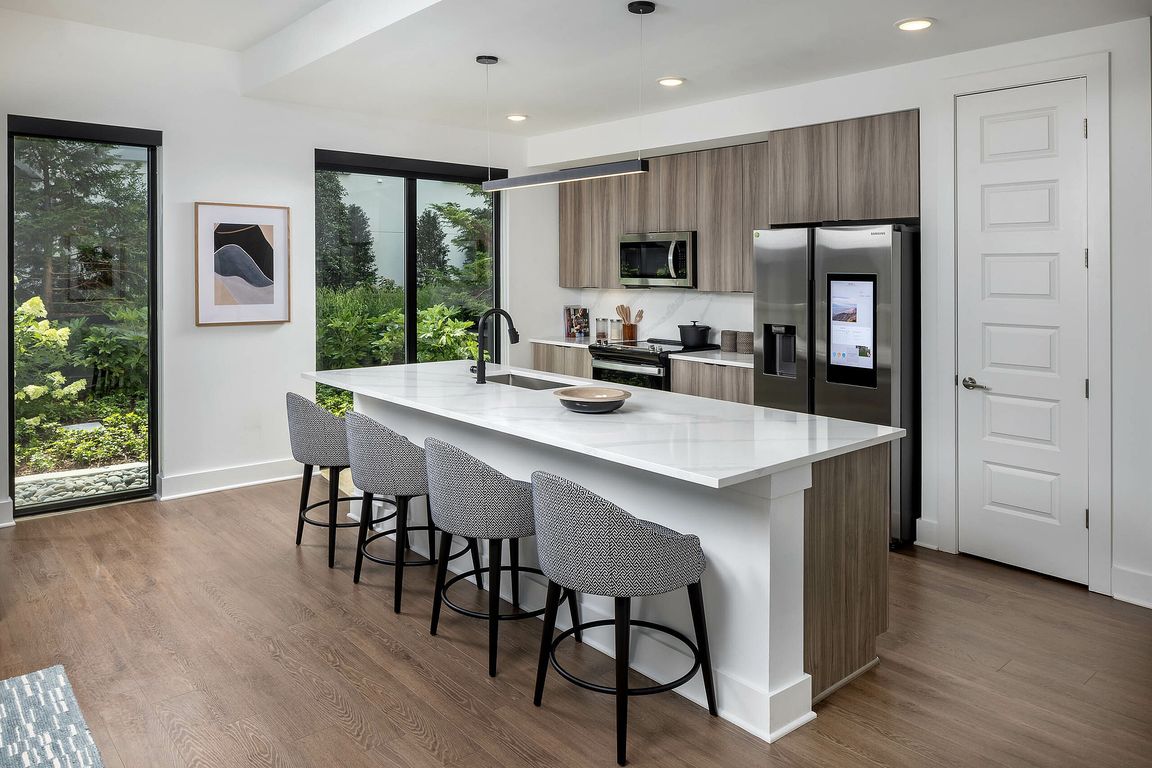 Gourmet kitchen with expansive island, custom light fixture and stainless-steel smart refrigerator