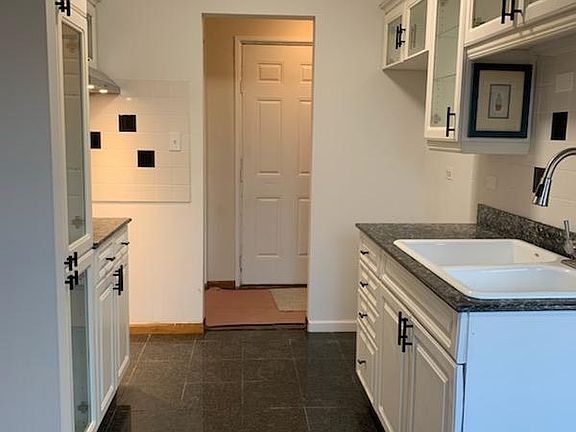 white glass front kitchen cabinets. granite counters and floor. stainless steel hood, and multi function faucet. Loads of cabinet space