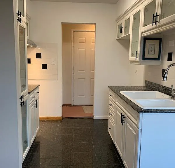 white glass front kitchen cabinets. granite counters and floor. stainless steel hood, and multi function faucet. Loads of cabinet space