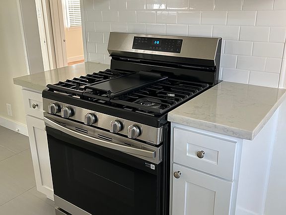 Example photo of style of stove, tile, countertops, and cabinetry that will be in unit