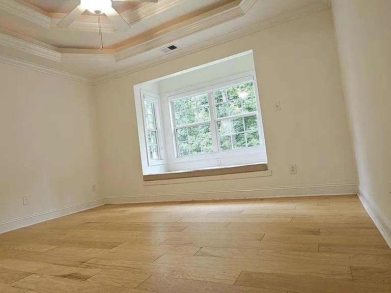 Primary suite offers a tray ceiling, abundant natural light, and a charming built-in window bench with storage.