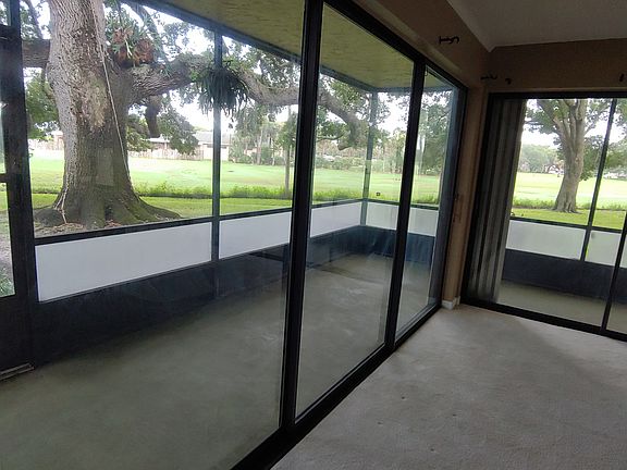 Wrap-around screened porch with view of trees and golf course driving range.