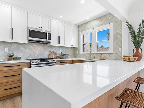 9' x 3' peninsula with waterfall countertop, all stainless steel appliances.
