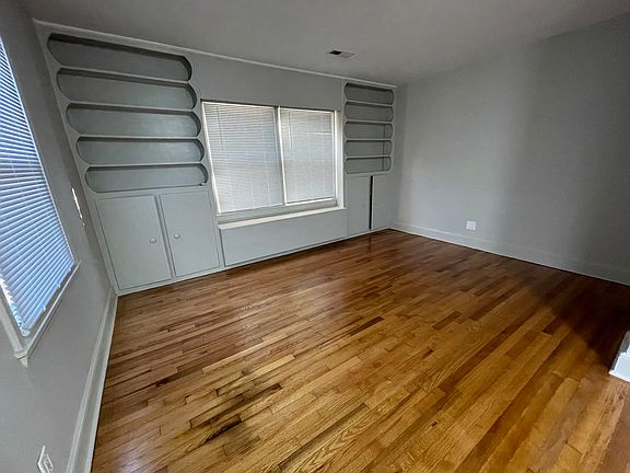 Living Room with built-ins, refinished hardwood flooring, new interior paint, new window blinds, and insulated energy efficient windows.