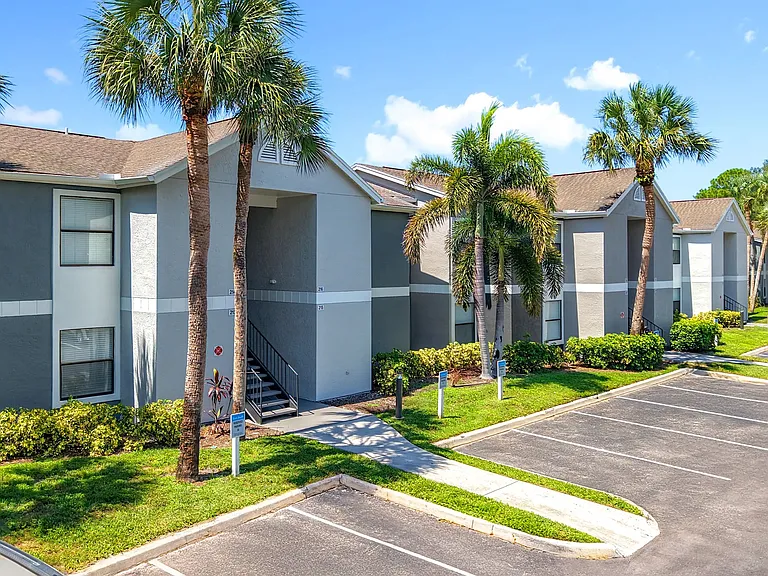 Enjoy vibrant Florida living at River Reach Apartments in Naples. This exterior showcases clean architecture, palm-lined walkways, and plenty of on-site parking.