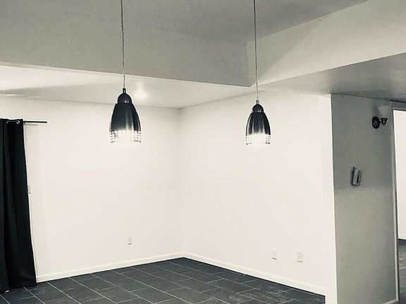Dining area with lights, back corner is living room area and there is also a sliding door leading to private patio.