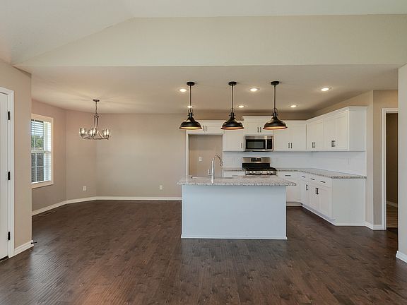 Granite kitchen counter bar with pendant lighting and dining area viewed from open concept family room