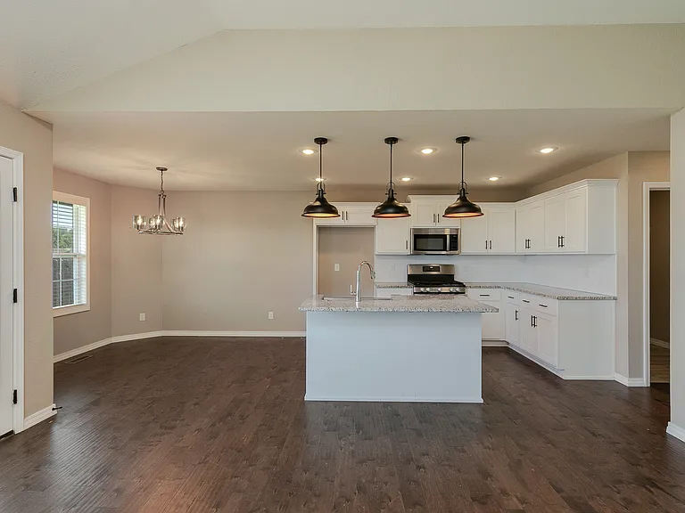 Granite kitchen counter bar with pendant lighting and dining area viewed from open concept family room