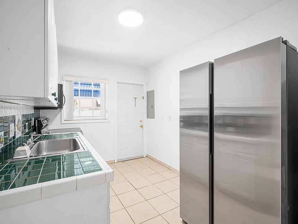 Kitchen - Kitchen features a large side-by-side stainless steel double-door refrigerator and generous cabinet storage space.