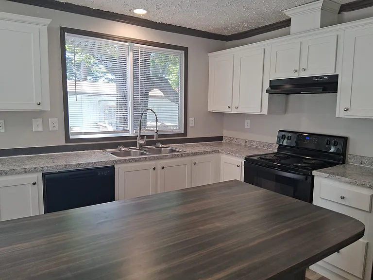 Spacious kitchen offering island eating, stove, fridge, and dishwasher with a double sink and wonderful counterspace under bright sunlight for cooking.