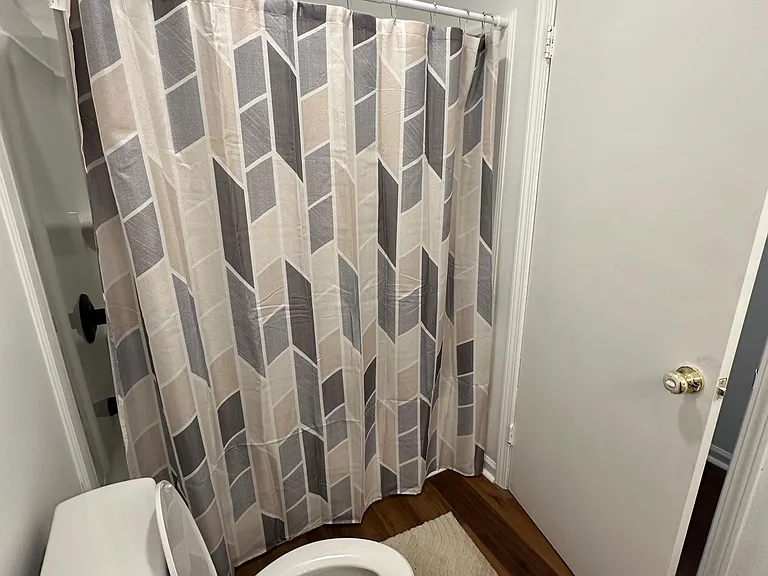 Full bathroom with a shower/tub combo, patterned shower curtain, and durable flooring for easy upkeep.