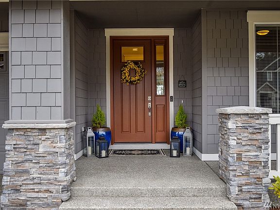 The dark hardwood door provides a striking contrast to the grey shingles and custom stonework. 