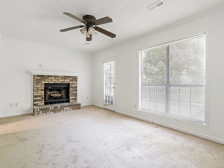 Cozy living room with wood-burning fireplace, large picture window, and access to the back deck