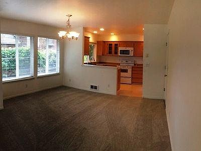Approaching kitchen from living room. Note all new custom blinds throughout. Dining area large enough for six- to eight-seat table. Barstools can be placed at open counter to kitchen.
