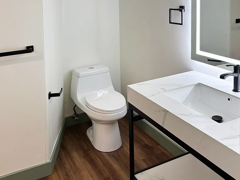 Bathroom with new toilet, quartz vanity sink, and LED lighted mirror.
