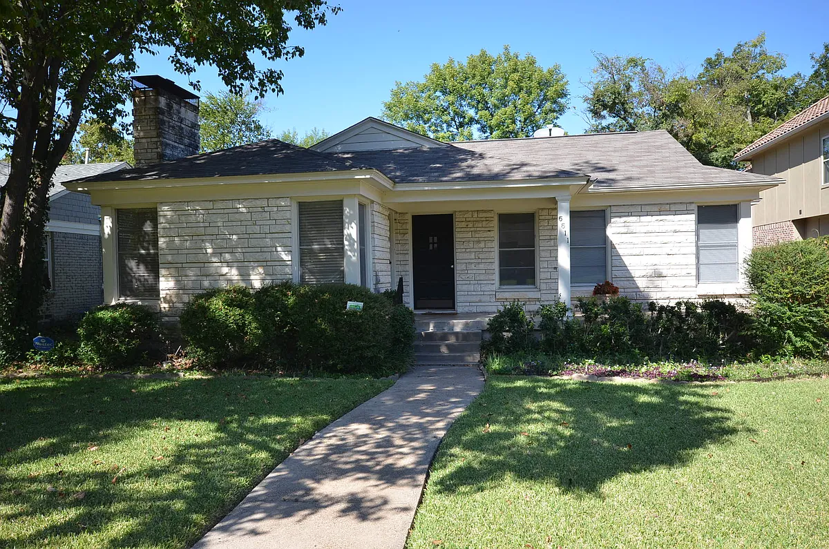 Single-story residence featuring a stone block facade, a paved walkway, and mature landscaping - 6611 Anita St
